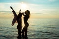 Two beautiful girls, students are dancing on the beach at sunset Royalty Free Stock Photo