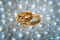 Two beautiful gold wedding rings lie among the white pearls, selective focus, close-up. Wedding concept Royalty Free Stock Photo