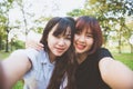 Two beautiful happy young asian women friends having fun together at park and taking a selfie. Royalty Free Stock Photo