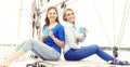 Two beautiful, happy and young girls enjoying a good summer day on a yacht and having a tea. Royalty Free Stock Photo