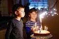 Two beautiful kids, little preschool boys celebrating birthday and blowing candles on homemade baked cake, indoor Royalty Free Stock Photo