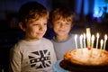 Two beautiful kids, little preschool boys celebrating birthday and blowing candles on homemade baked cake, indoor Royalty Free Stock Photo