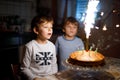 Two beautiful kids, little preschool boys celebrating birthday and blowing candles Royalty Free Stock Photo