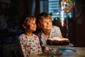 Two beautiful kids, little preschool boys celebrating birthday and blowing candles on homemade baked cake, indoor Royalty Free Stock Photo