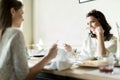 Two beautiful ladies eating in a restaurant while having a conve