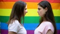 Two beautiful lesbians standing on rainbow flag background, minority rights