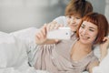 Two beautiful lesbians taking a selfie while lying on the bed