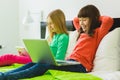 Two beautiful little sisters sitting on bed and play with a Tablet or laptop Royalty Free Stock Photo