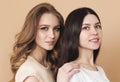 Two beautiful multicultural young women over beige background