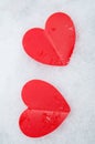 Two beautiful romantic red hearts vertical frame together on a white snowy