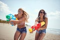 Two sexy young female with sunglasses playing with water-gun on sandy beach Royalty Free Stock Photo