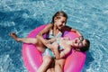 Two beautiful sisters floating on pink donuts in a pool. Playing tickles and smiling. Fun and summer lifestyle Royalty Free Stock Photo