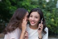 Two beautiful smiling girls sharing a secret in the park Royalty Free Stock Photo