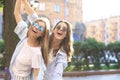 Two beautiful smiling girls in trendy summer clothes posing on street background. Models are having fun and hugging Royalty Free Stock Photo