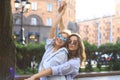 Two beautiful smiling girls in trendy summer clothes posing on street background. Models are having fun and hugging Royalty Free Stock Photo