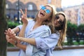 Two beautiful smiling girls in trendy summer clothes posing on street background. Models are having fun and hugging Royalty Free Stock Photo