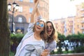 Two beautiful smiling girls in trendy summer clothes posing on street background. Models are having fun and hugging Royalty Free Stock Photo