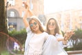 Two beautiful smiling girls in trendy summer clothes posing on street background. Models are having fun and hugging Royalty Free Stock Photo