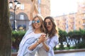 Two beautiful smiling girls in trendy summer clothes posing on street background. Models are having fun and hugging Royalty Free Stock Photo