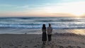 Two beautiful stylish girls look at the cloudy sunset on the shores of the mediterranean sea