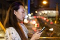 Two Beautiful stylish and smiling Young Woman Using Smartphone in Night City Street Full of Neon Light. back view Royalty Free Stock Photo