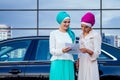 Two beautiful and successful multinational muslim business women entrepreneur in stylish hijab and turban holding paper Royalty Free Stock Photo