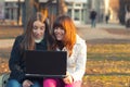 Two beautiful teenage girls having fun with notebook in the park Royalty Free Stock Photo