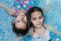 Two beautiful teenager girls floating in a pool and looking at the camera. Fun and summer lifestyle Royalty Free Stock Photo