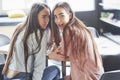 Two beautiful twin girls spend time. Sisters relaxing in a cafe and having fun together and whispering Royalty Free Stock Photo