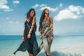 Two beautiful twin sisters in elegant dresses having fun on tropical beach Royalty Free Stock Photo