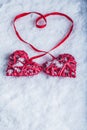 Two beautiful vintage red hearts tied together with a ribbon on a white snow background. Love and St. Valentines Day concept. Royalty Free Stock Photo