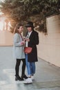 two beautiful woman with casual clothing smiling at sunset and using mobile phone. back light. City background Royalty Free Stock Photo