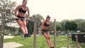 Two beautiful women doing various bodyweight exercises at the horizontal bar