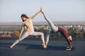 Two beautiful women doing yoga asana virabhadrasana on the roof Royalty Free Stock Photo