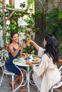 two beautiful women friends clinking lemonades for cheers and eating breakfast in cafe Royalty Free Stock Photo