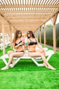 Two beautiful women having cocktails together by the swimming pool. summer time Royalty Free Stock Photo