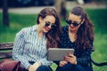 Two beautiful women laughing watching media content together in a digital tablet Royalty Free Stock Photo