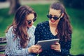 Two beautiful women laughing watching media content together in a digital tablet Royalty Free Stock Photo