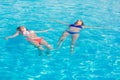 Two beautiful women lying on swimming pool water surface Royalty Free Stock Photo