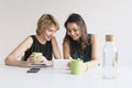 Two beautiful women at the office searching for information on tablet or mobile phone. White background. Modern office concept. Royalty Free Stock Photo