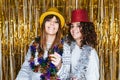 Two beautiful women in pajamas and some Christmas costumes enjoying the party together on New Year`s Eve. They are looking at the