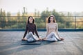 Two beautiful women perform meditative pose on the roof