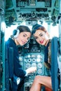 Two beautiful women pilot wearing uniform. Looking at camera through the cockpit. Pilots in cockpit. Girls looking at