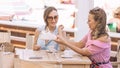 Two beautiful women showing each other and discussing purchases white shoes after a shopping day in an Italian beach cafe Royalty Free Stock Photo