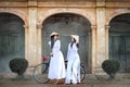 Two beautiful women in Vietnam`s national costume Riding a bicycle to see ancient buildings Royalty Free Stock Photo