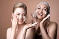 Two beautiful women, young and mature gray-haired female applying foaming cleanser