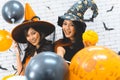 Two beautiful young asian woman in witch halloween costume holding balloon on white brick background decorated Royalty Free Stock Photo