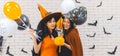 Two beautiful young asian woman in witch halloween costume holding pumpkin Jack O Lantern and balloon on white brick background Royalty Free Stock Photo