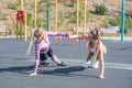 Two beautiful, young and athletic girls doing push-ups on a street playground. Royalty Free Stock Photo