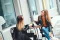 Two beautiful young blonde women drinking coffee and gossiping in nice restaurant outdoor Royalty Free Stock Photo